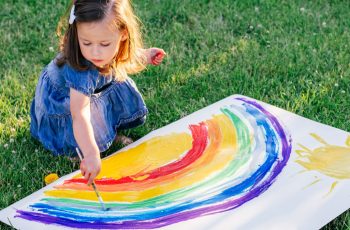 дівчинка малює райдугу на великому аркуші паперу