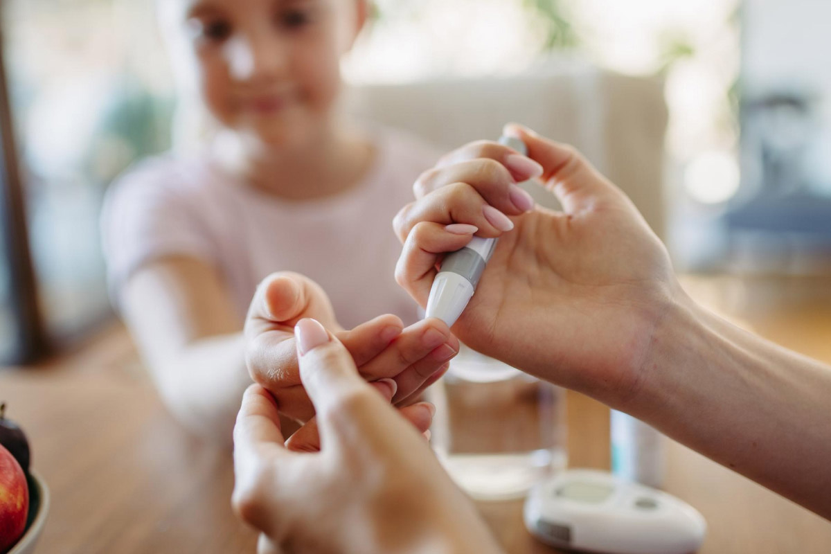 мама проводить дитині вимірювання рівня глюкози