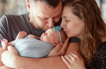 мама та тато цілують на радостях свою новонароджену дитину