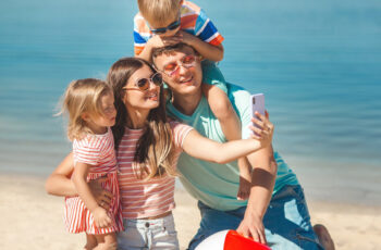 мама, тато та двоє дітей весело проводять час та відпочивають на пляжі