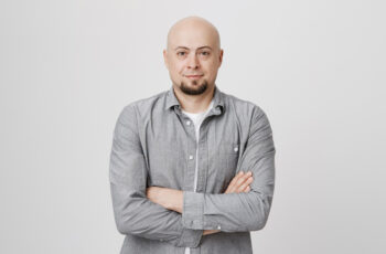 на білому фоні зображений чоловік із облисінням, він має повністю позбавлену волосся шкіру голови