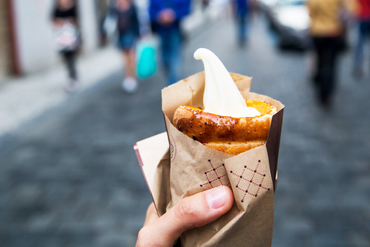 турист тримає в руці трубочку із кремовою начинкою