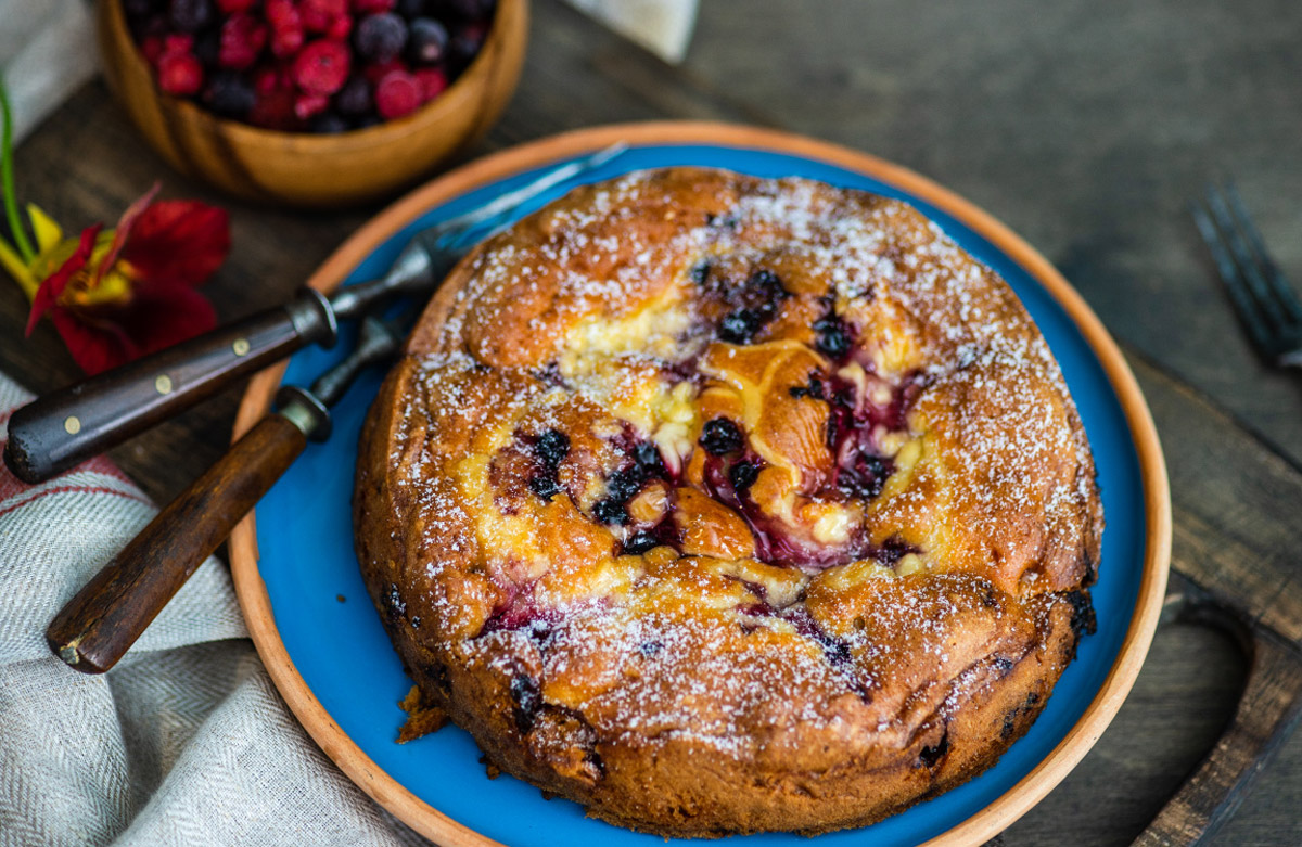 ягідна шарлотка присипана цукровою пудрою на синьому блюді