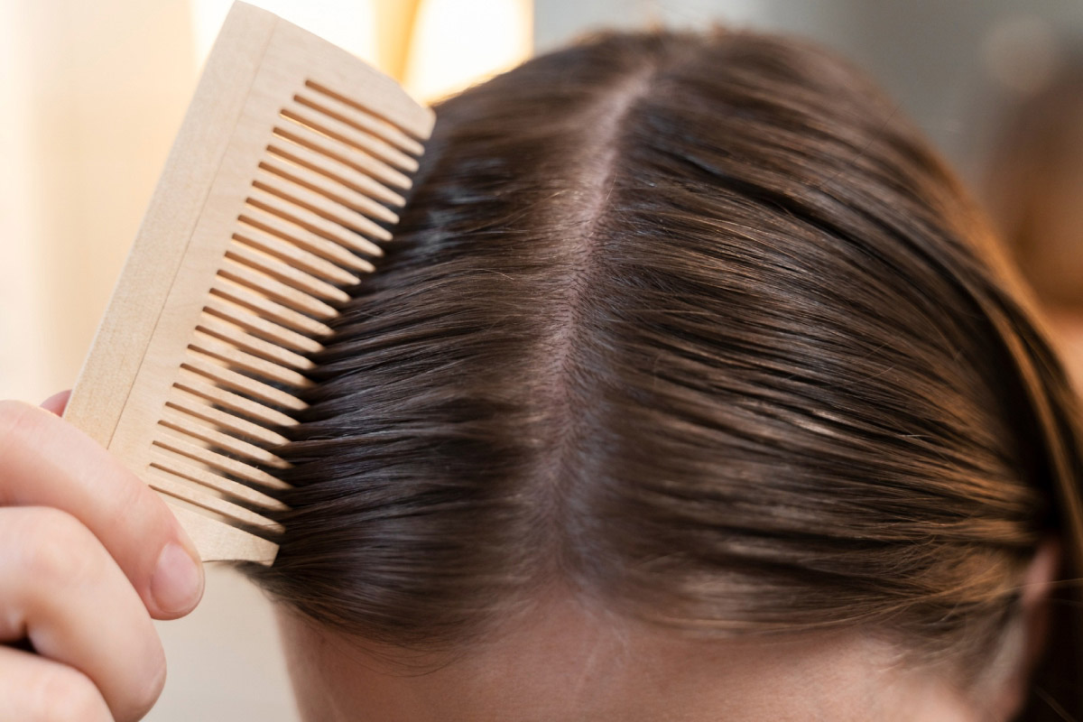 жінка гребінцем розчісує волосся