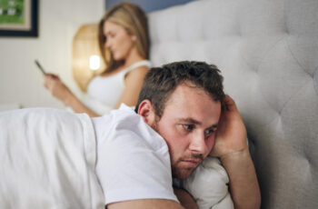 жінка та чоловік у ліжку перед сном, чоловік відвернувся та, вочевидь, є стурбованим