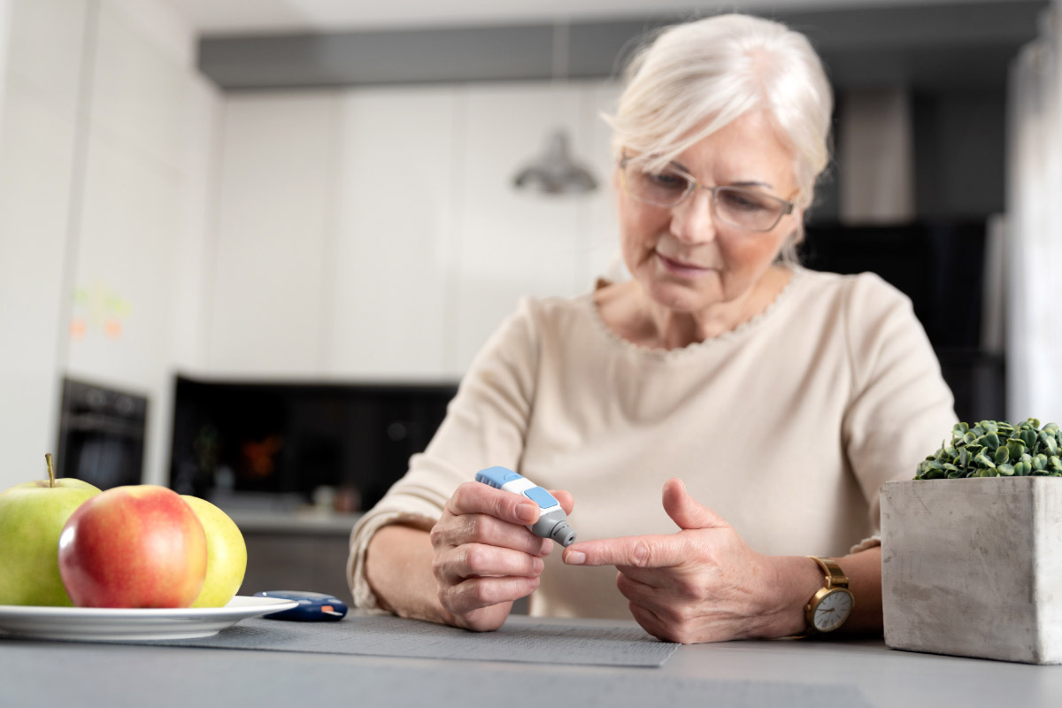 жінка, яка на кухні сидить, та вимірює рівень глюкози в крові