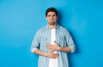 чоловік має вираз обличчя болі через дискомфорт у шлунку