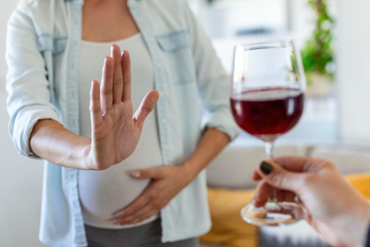 на зображенні показано, як вагітна жінка відмовляється від келиху алкоголю, в цьому випадку від вина