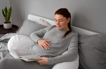 вагітна жінка відпочиваю в ліжку у себе в дома, читаючи книгу