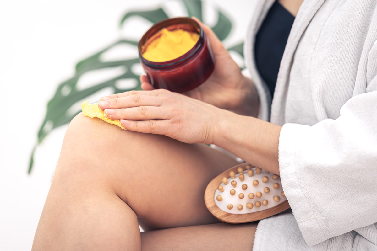 жінка наносить скраб для шкіри на ноги