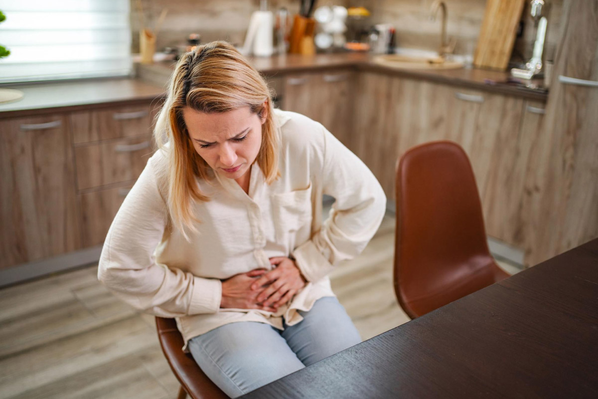 жінка переживає дискомфорт у шлунку