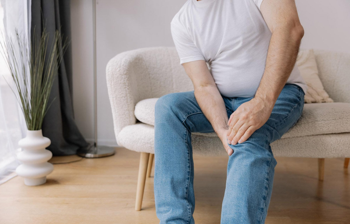 зображення чоловіка, що сидить на кріслі, та тримається за ноги, бо вони болять