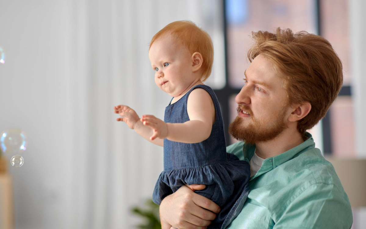 батько тримає на руках свою новонароджену дитину