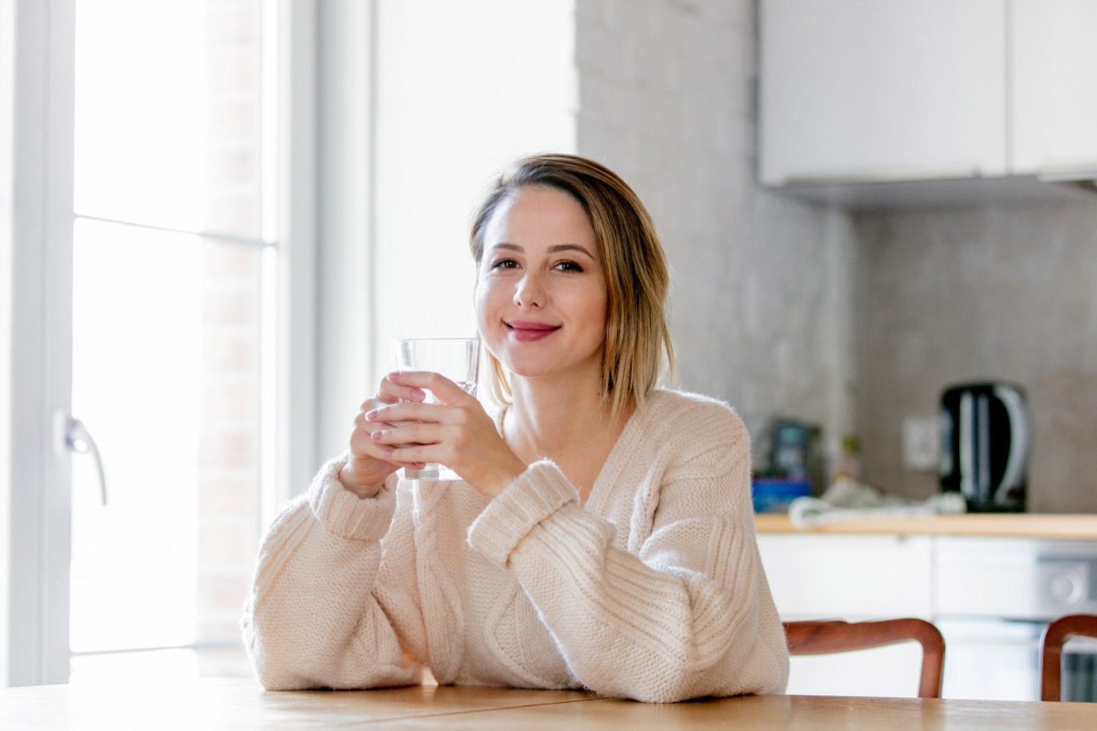 дівчина сидить на кухні та п'є воду