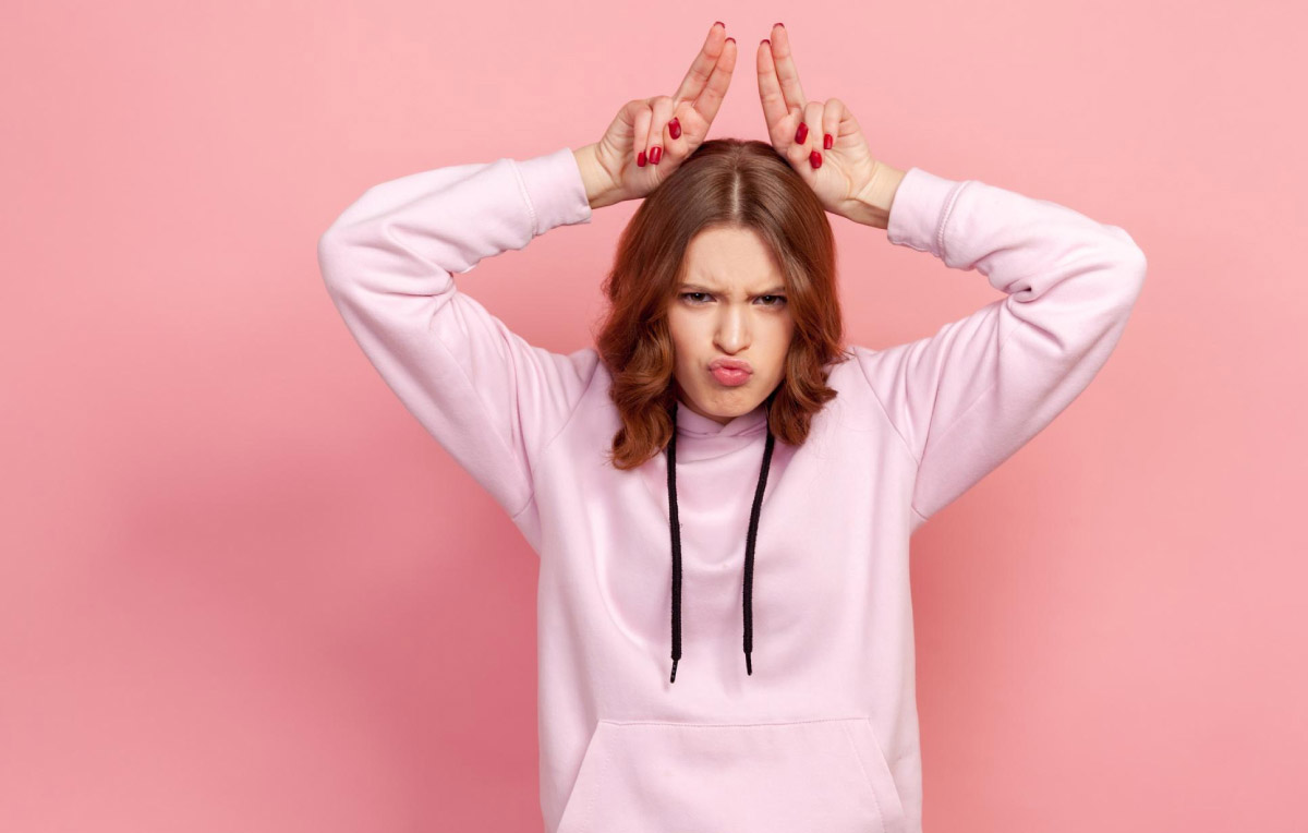 дівчинка, яка робить гримаси, поставила умовні ріжки собі на голову