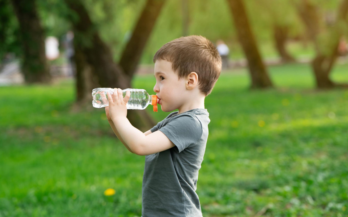 дитина у парку п'є воду