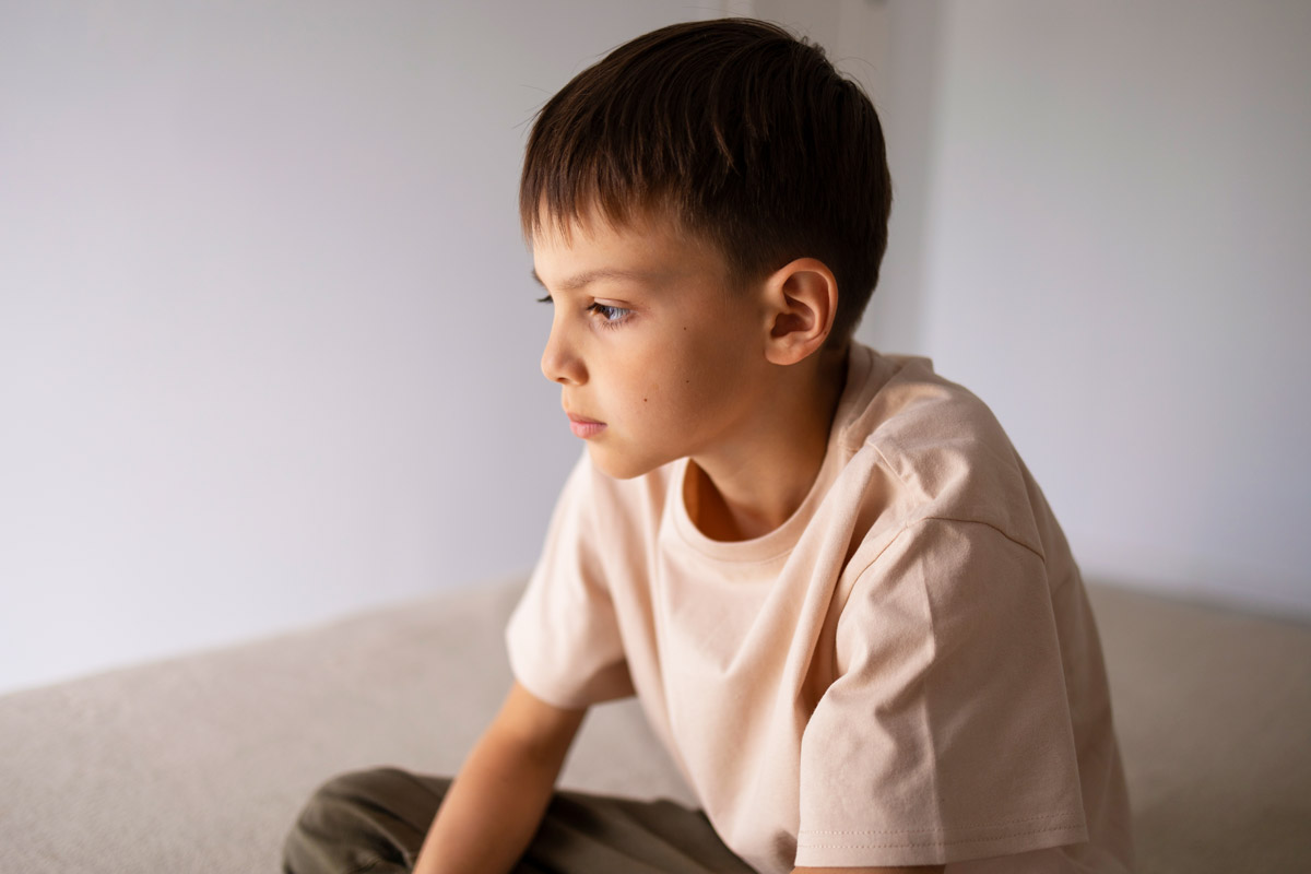 хлопчик сидить на підлозі із задумливим виразом обличчя