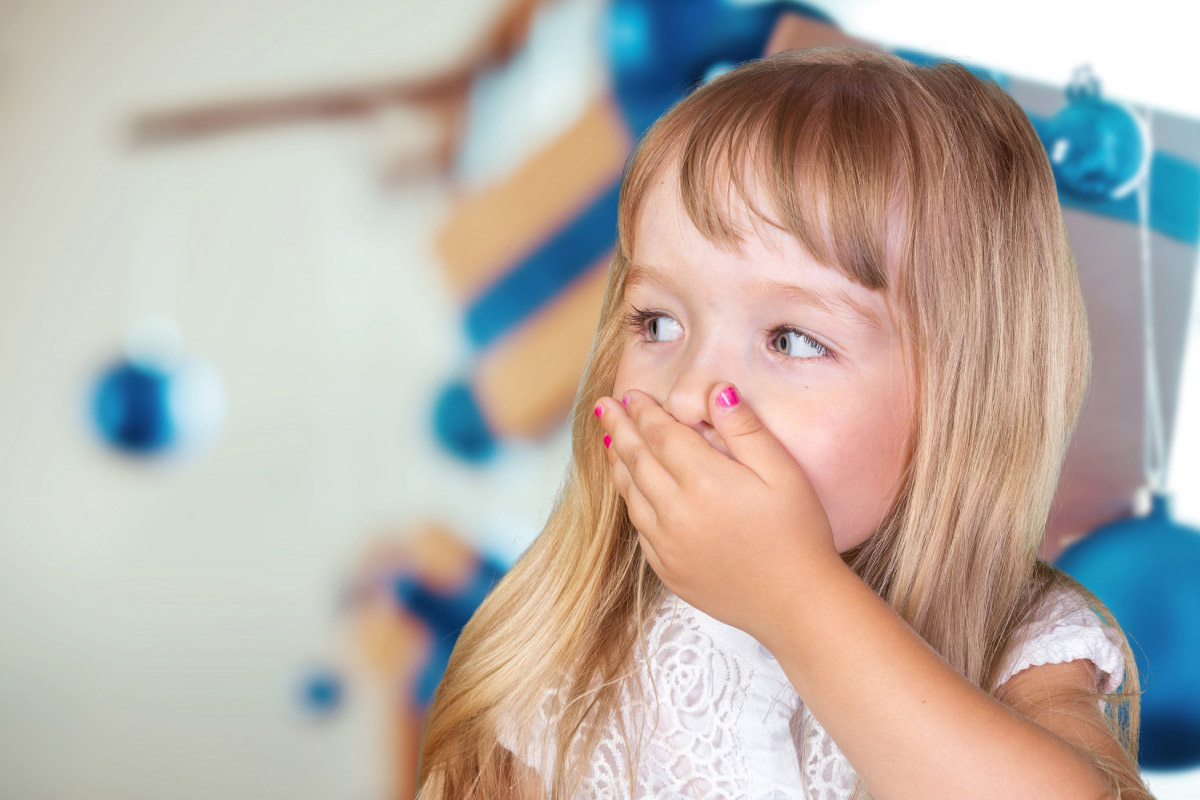 маленьку дівчинку нудить, вона прикриває обличчя руками через погане самопочуття