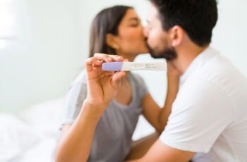 подружжя цілується, адже вони щасливі бачити позитивний тест на вагітність