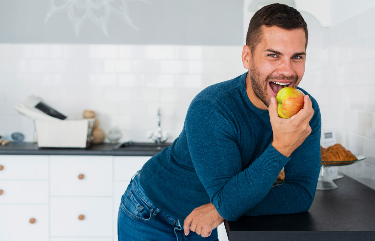 чоловік посміхається та їсть яблуко