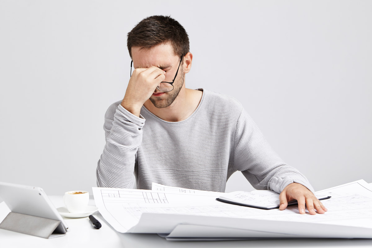 чоловік сидить втомлений за робочим столом