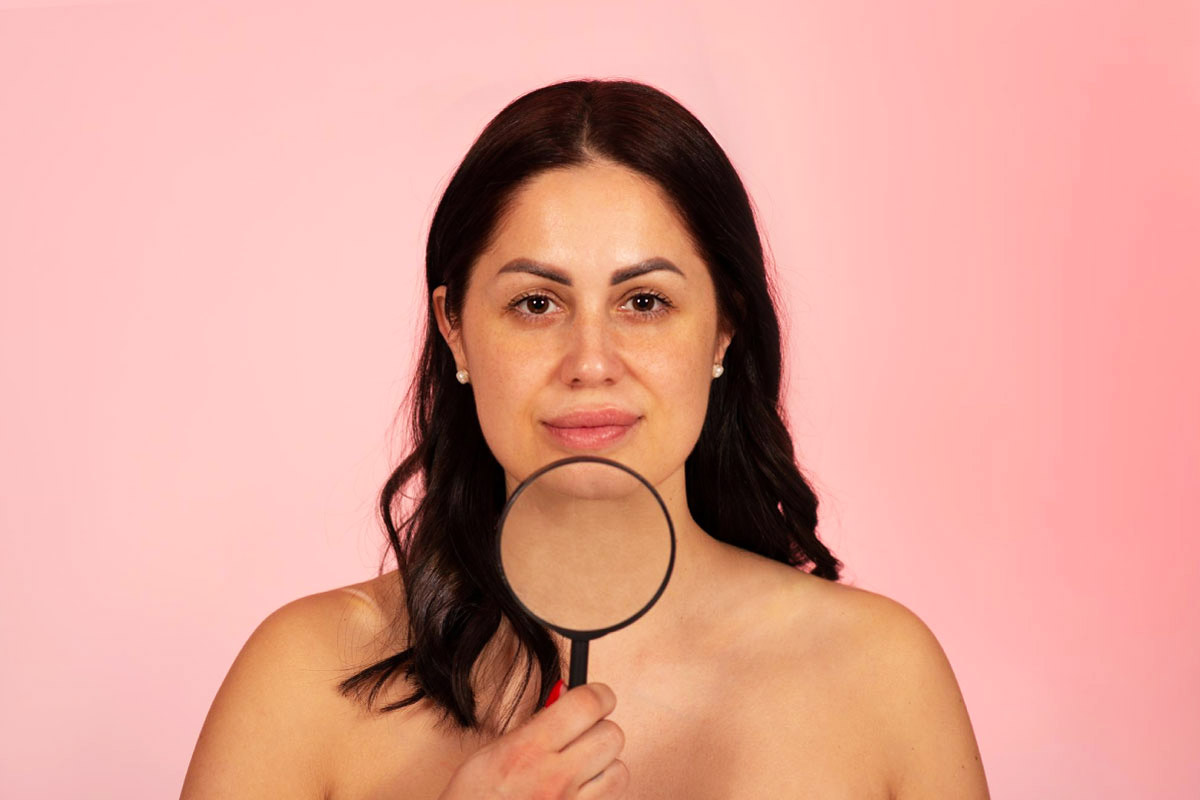 жінка тримає лупу біля шкіри