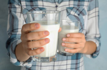 людина тримає склянку молока в руці