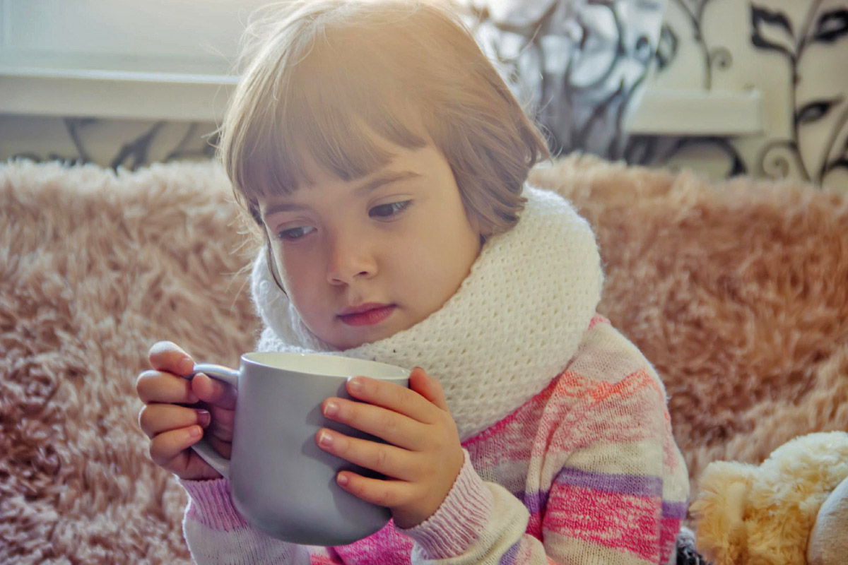 маленька дитина п'є чай при трахеїті