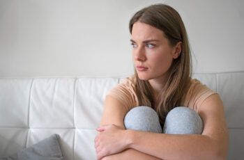 засмучена жінка сидить на дивані - тривожність