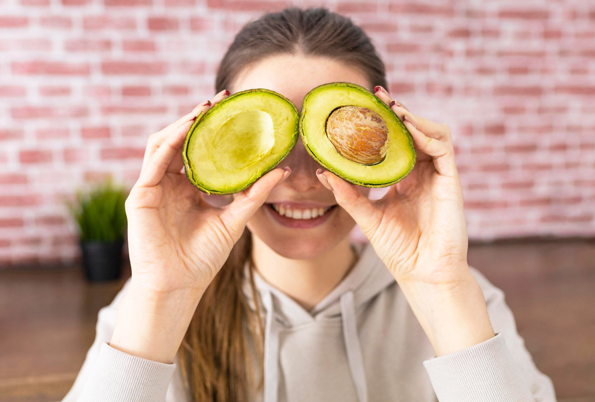 жінка приклала до обличчя екзотичний фрукт наче очі