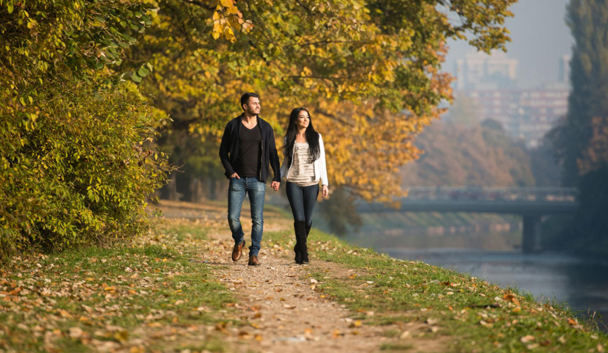 жінка та чоловік гуляють по парку біля озера