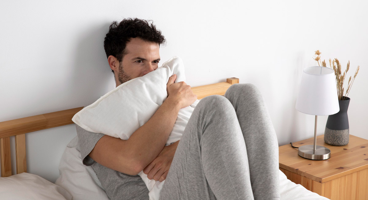 чоловік сидить на своєму ліжку та виглядає стурбовано