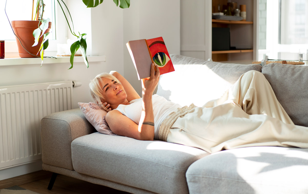 жінка читає вдома книгу