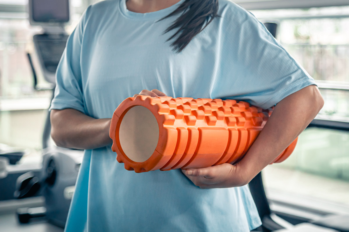 жінка з ролером для вправ міофасціального релізу