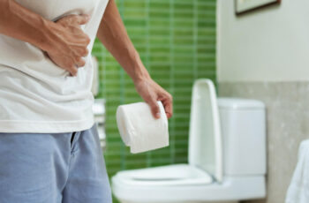 біль у животі, чоловік стоїть у вбиральні