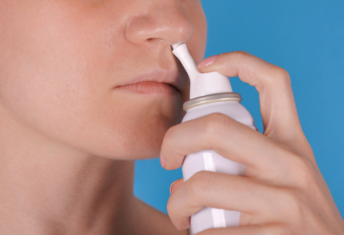 дівчина використовує спрей для носа