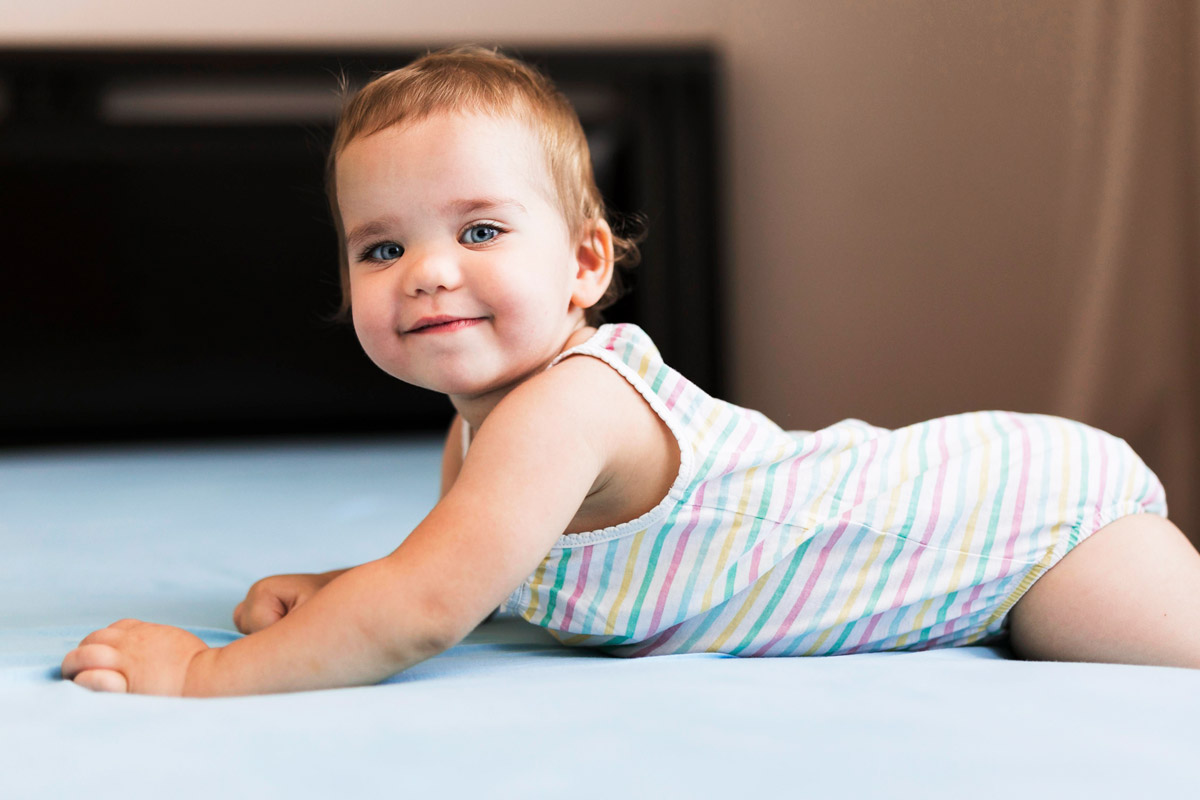 дитинка лежить на ліжку