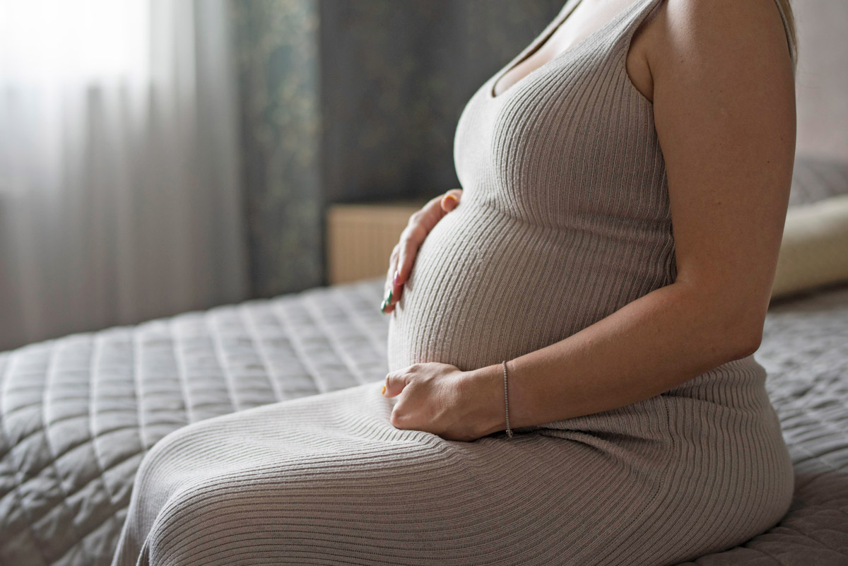 вагітна жінка сидить на ліжку