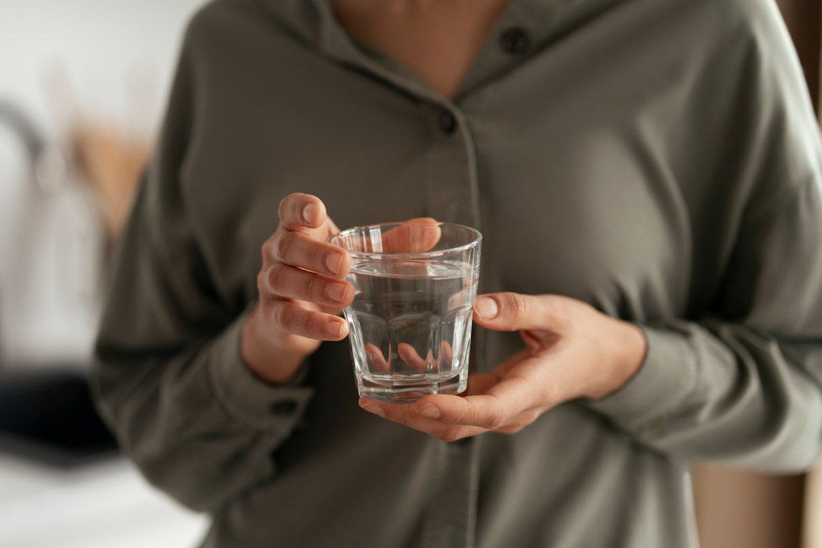 людина тримає склянку води